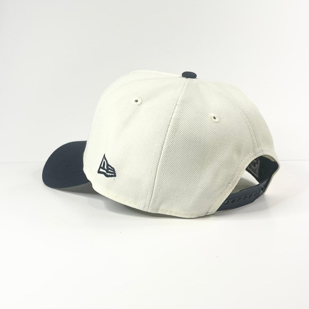 White baseball cap with navy brim on a white background